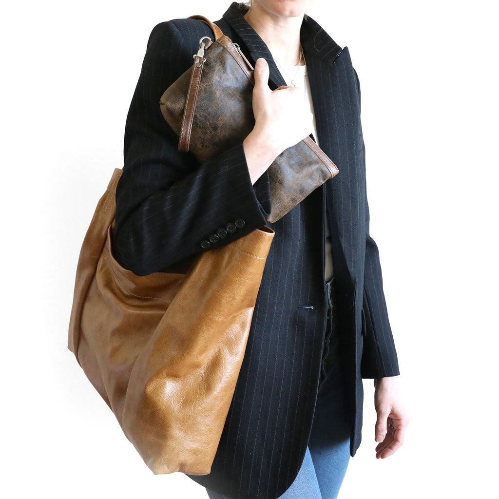 close-up of model with scarborough in light saddle holding a zip pouch large in dingo 